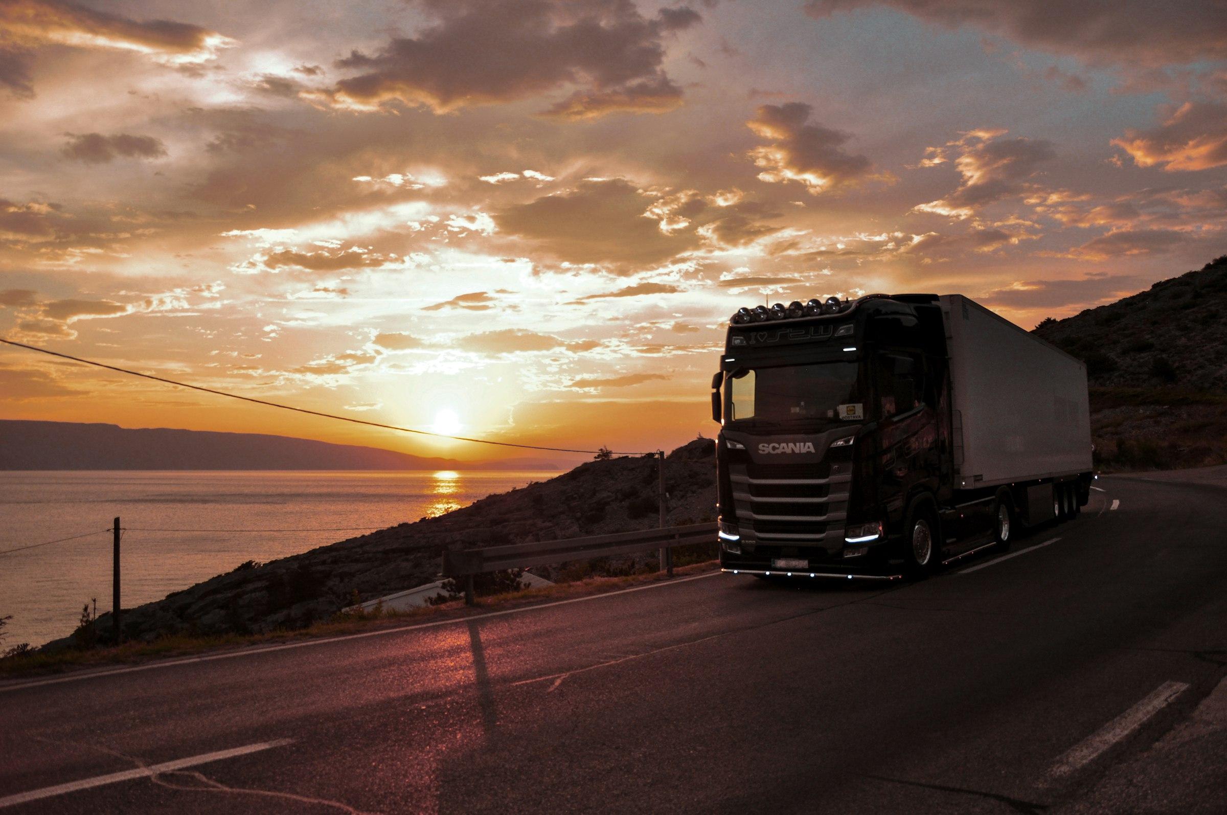 Camión en una carretera junto al mar al atardecer